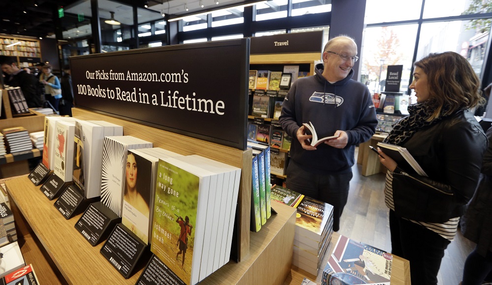 Customer Jeff Edward, left, talks with Amazon employee Sarah Gelman as Edward shops at the opening day for Amazon Books, the first brick-and-mortar retail store for online retail giant Amazon, Tuesday, Nov. 3, 2015, in Seattle. The company says the Seattle store, coming two decades after it began selling books over the Internet, will be a physical extension of its website, combining the benefits of online and traditional book shopping. Prices at the store will be the same as books sold online. (AP Photo/Elaine Thompson)